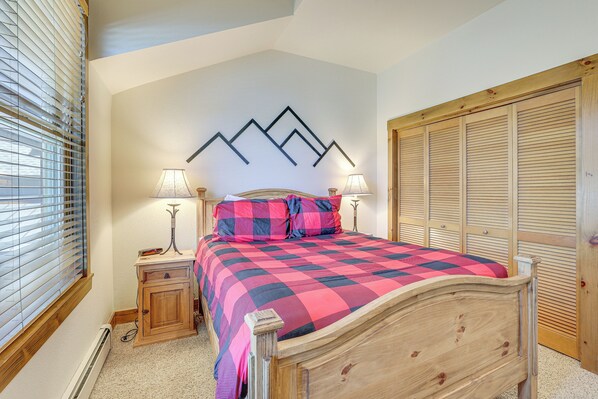 A bedroom with a wooden bed, a nightstand, a lamp, and a closet.