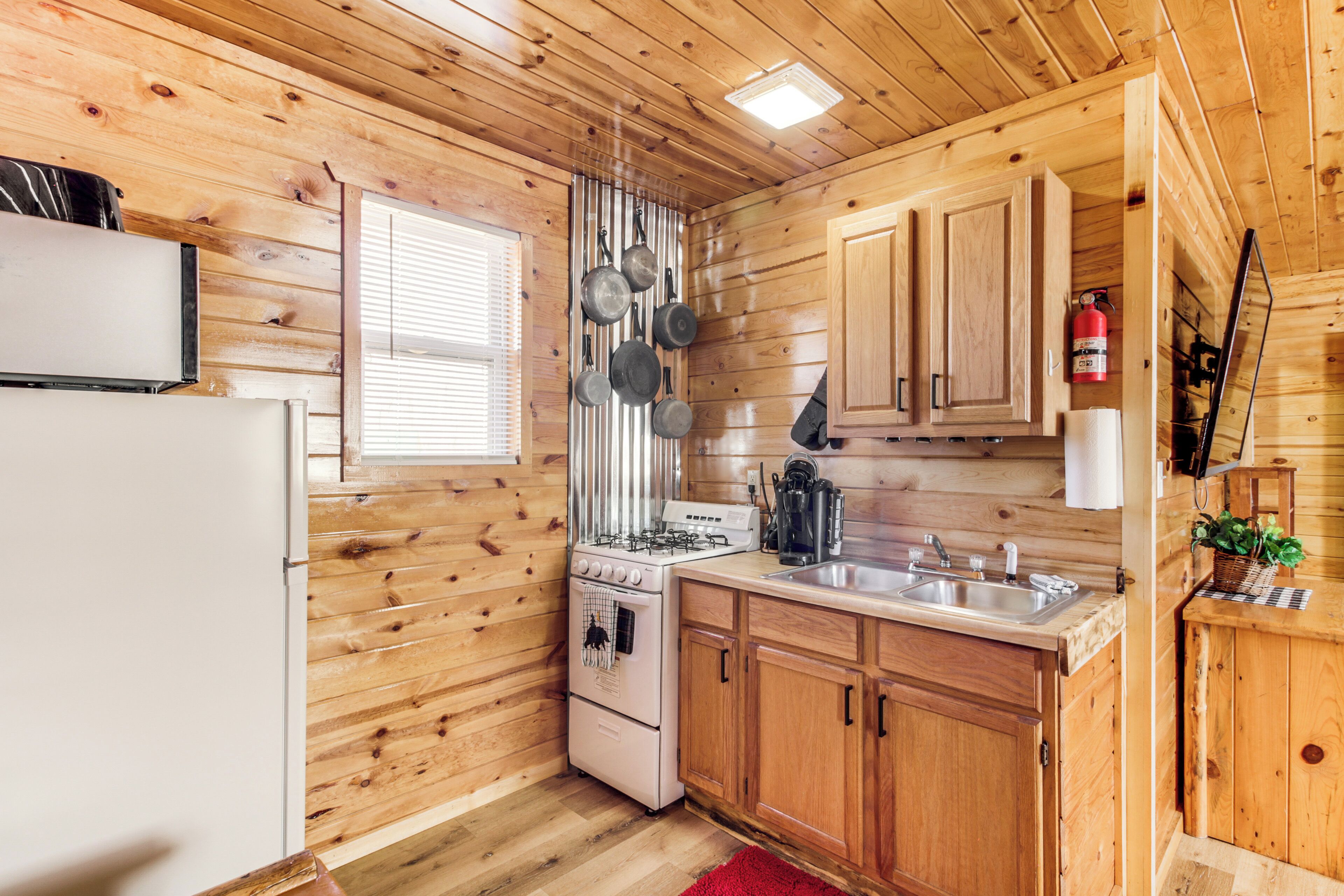 A kitchen with wooden walls, a stove, a sink, and cabinets.