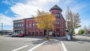 Ein rotes Backsteingebäude mit einem Turm, eine Straße davor und geparkte Autos.
