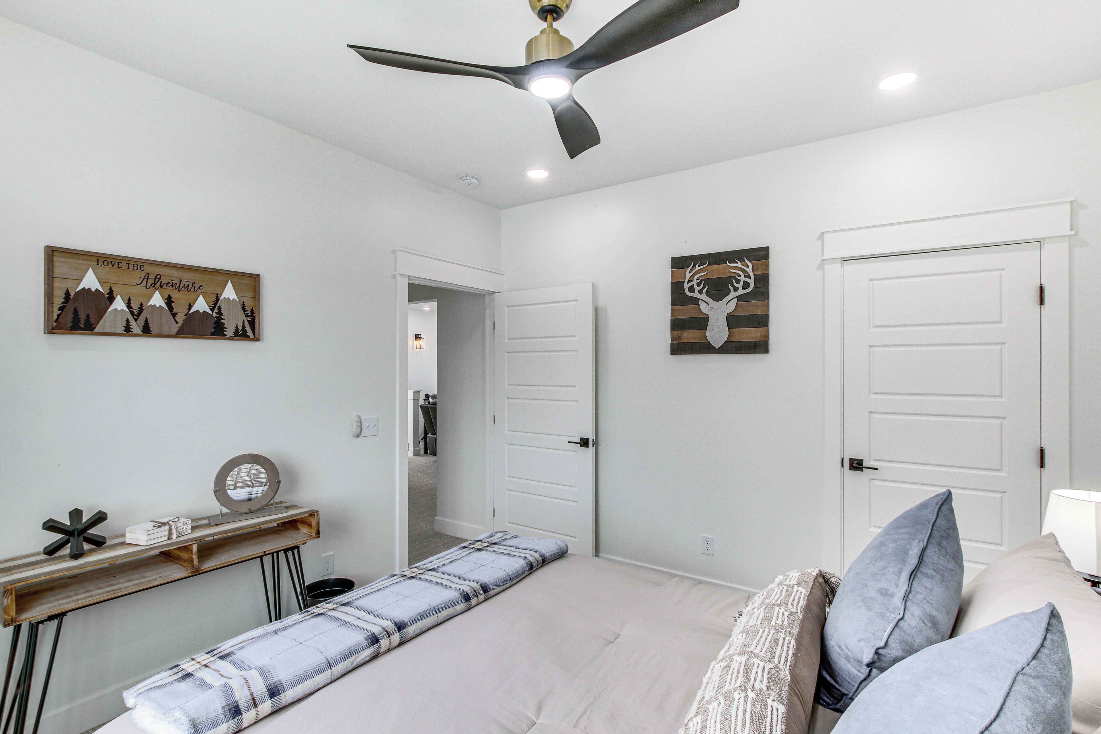 A bedroom with a bed, bedside tables, a ceiling fan, and artwork on the walls.