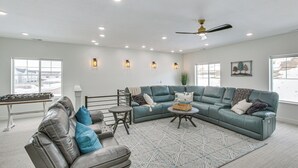 Ein geräumiges Wohnzimmer mit einem Ecksofa, einem Ledersessel, einem Couchtisch und einem Kicker.