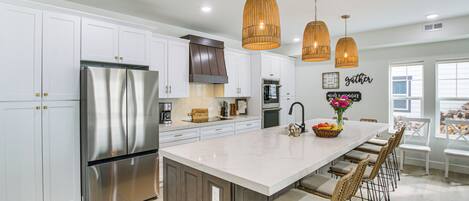 A modern kitchen with white cabinets, stainless steel appliances, and a central island with bar stools.