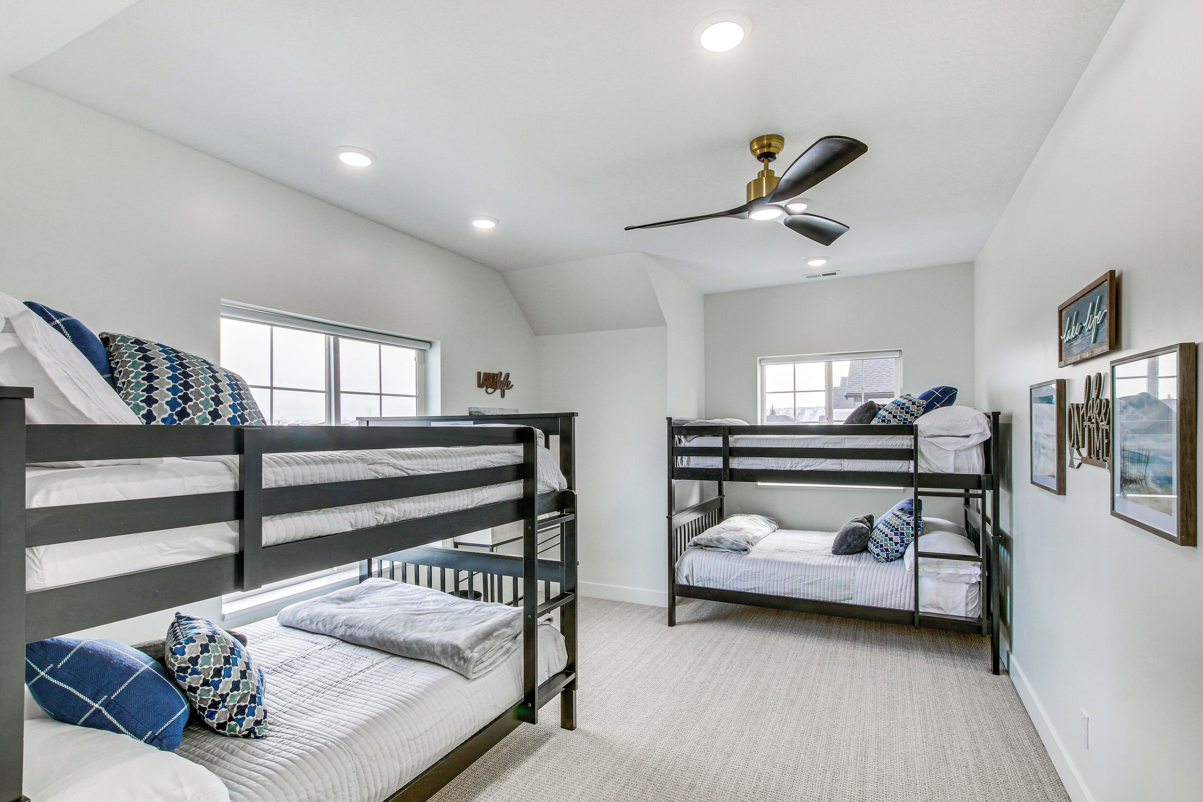 A room with bunk beds, a ceiling fan, and a window.