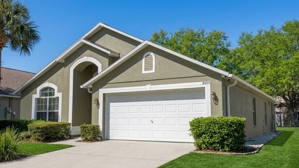 A single-story house with a garage, a well-maintained lawn, and a palm tree.