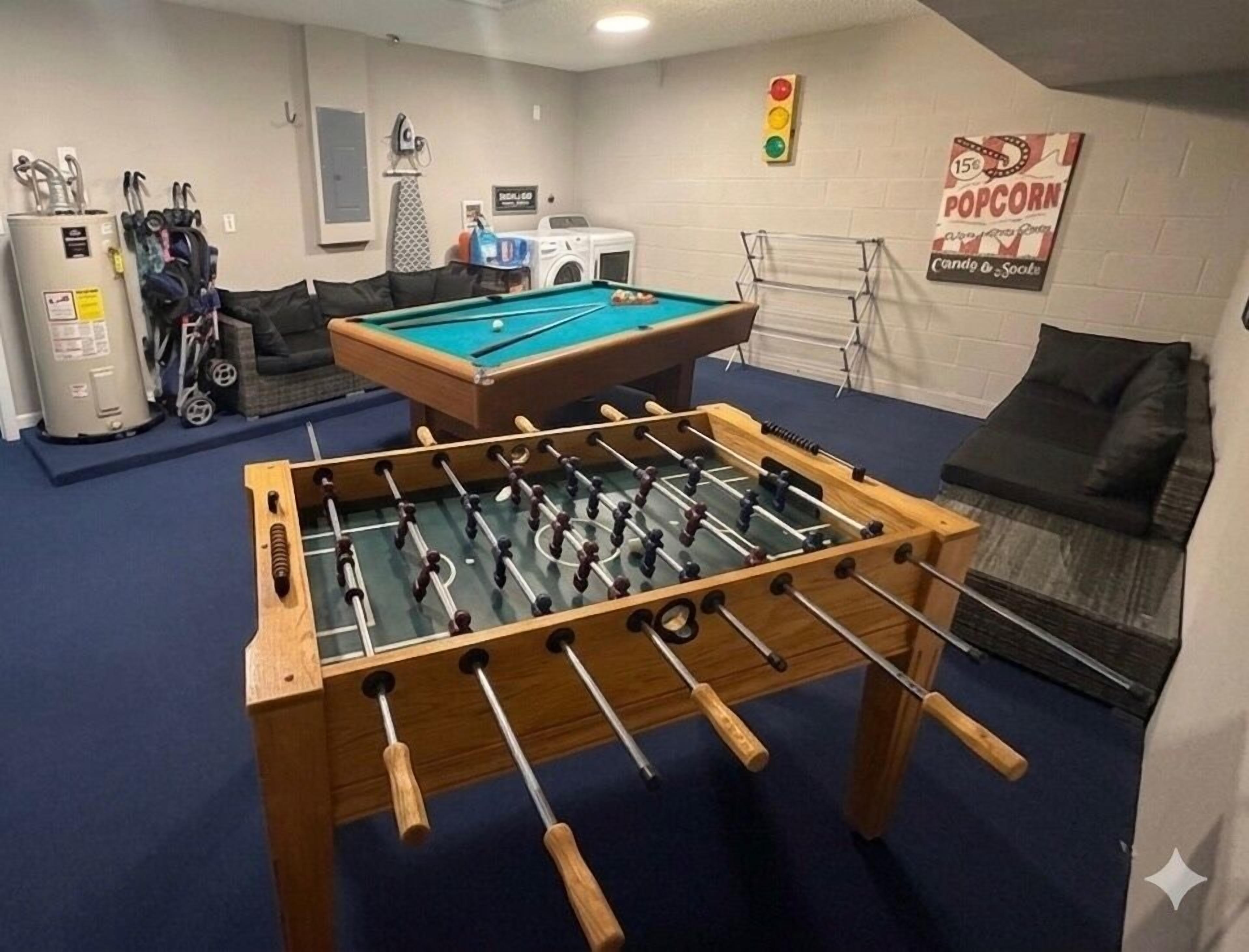 A room with a foosball table, a pool table, a washing machine, and a dryer.