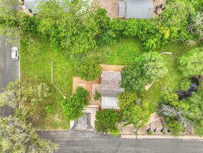 An aerial view of a residential property with a house, a driveway, and surrounding greenery. - Town Creek Cabin Walk to Main St. (Fredericksburg)