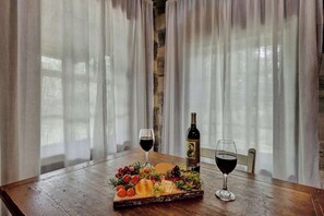 Una mesa de madera con una tabla de embutidos, dos copas de vino tinto y una botella de vino.