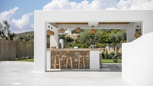 A white outdoor bar area with stone accents, wicker pendant lights, and a stone wall. - Villa Elaia is the perfect retreat for those seeking a luxurious a getaway. (Rhodes)