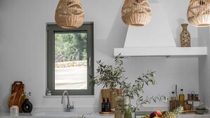 A kitchen with wicker pendant lights, a window with a view, a sink, and a fruit bowl on the counter. - Villa Elaia is the perfect retreat for those seeking a luxurious a getaway. (Rhodes)