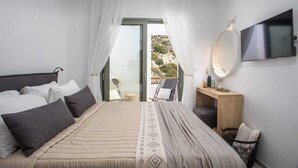 A bedroom with a bed, a bedside table, a mirror, and a TV. - Villa Elaia is the perfect retreat for those seeking a luxurious a getaway. (Rhodes)
