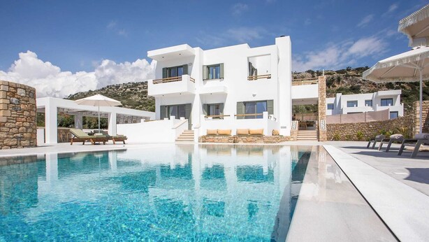 A modern white villa with a swimming pool, stone walls, and a view of the surrounding landscape. - Villa Elaia is the perfect retreat for those seeking a luxurious a getaway. (Rhodes)