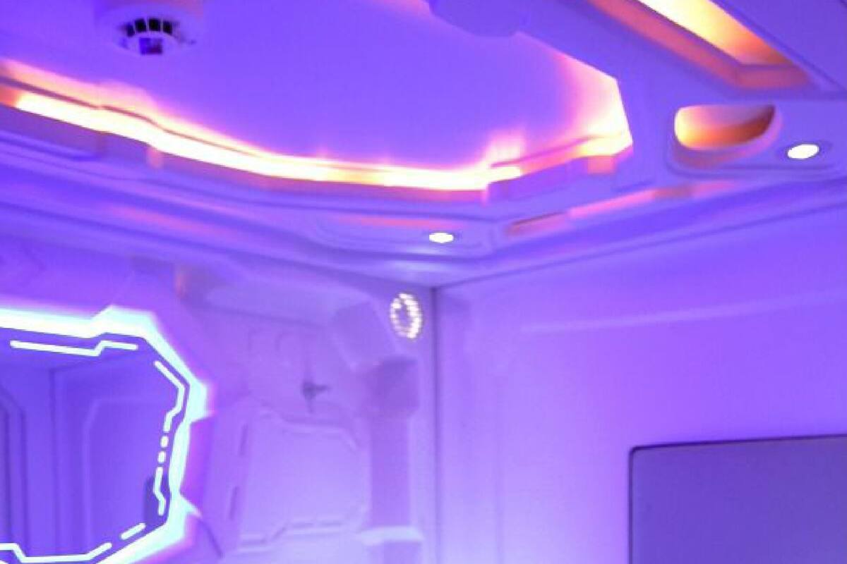 A room with a bed, a wall-mounted TV, and a ceiling with a unique light fixture.
