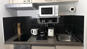 Une cuisine compacte équipée d’un four à micro-ondes, d’une machine à café, d’un grille-pain et d’un évier.