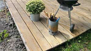 A wooden deck with a table and chairs, a grill, and a potted plant. - Luxe Safaritent, Midden in de Natuur (Hensbroek)