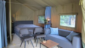 A tented accommodation with a bed, sofa, and seating area. - Luxe Safaritent, Midden in de Natuur (Hensbroek)