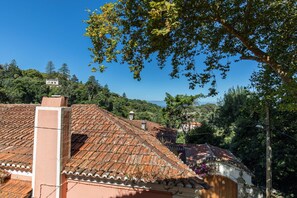 Un bâtiment traditionnel, doté d’un toit en tuiles de terre cuite, entouré d’une végétation luxuriante et surplombé d’un ciel bleu azur.