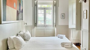Ein Hotelzimmer mit einem großen Bett, einem kleinen Tisch, einem Bild an der Wand und einem Fenster mit Vorhängen.