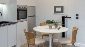 A modern kitchen with built-in appliances, a dining area with a round table and wicker chairs, and a pendant light fixture.