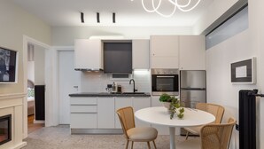 A modern kitchen with white cabinets, a black countertop, and a round dining table with wicker chairs.