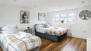 Une chambre avec deux lits, une fenêtre donnant sur un beau paysage et des œuvres d’art mural.
