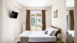 Une chambre d’hôtel avec un lit, un téléviseur fixé au mur, une table de chevet avec une lampe et une vue sur l’extérieur par la fenêtre.