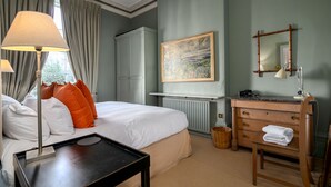 Une chambre d’hôtel avec un lit, une commode, un miroir et un tableau accroché au mur.