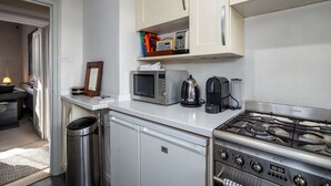 Une cuisine compacte équipée d’un four à micro-ondes, d’une bouilloire et d’une cuisinière à gaz.