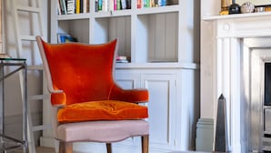 Une pièce avec un fauteuil en velours rouge, une bibliothèque et une cheminée.