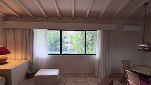 Una habitación con un ventanal grande, una mesa de comedor, un banco y una lámpara.