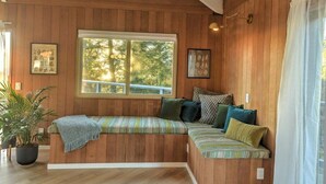 A wooden-paneled room with a built-in bench, a large window, and a potted plant.