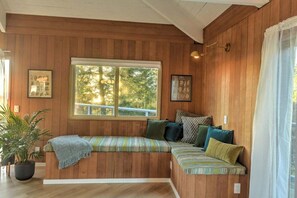 A wooden-paneled room with a built-in bench, a large window, and a potted plant.