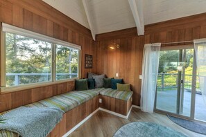A wooden interior with a bench seating area, large windows, and a sliding glass door.