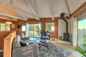 A modern living room with a sofa, coffee table, and a fireplace. - Stellar View | Panoramic Ocean Views & Hot Tub (Sea Ranch)