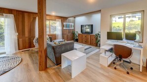A modern living room with a sofa, coffee table, TV, and workspace.