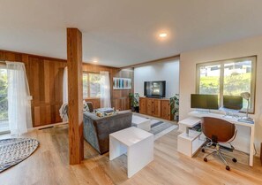 A modern living room with a sofa, coffee table, TV, and workspace.