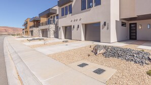 A modern multi-story residential building with balconies, a stone facade, and a clear view of the surrounding landscape. - Modern 3BR, Next to Pool, Hot Tub, Golf Views (St. George)