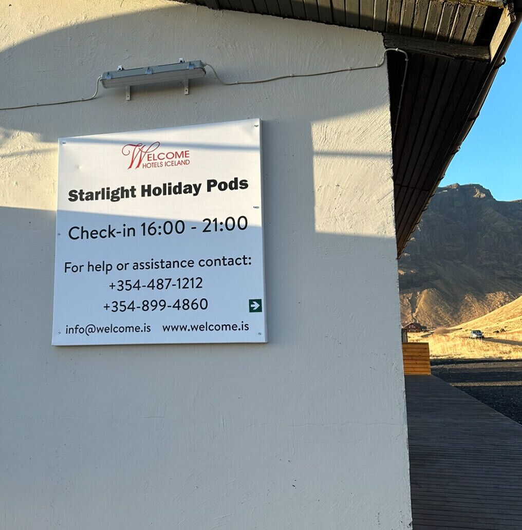 Señal de Welcome Hotels Islandia, Starlight Holiday Pods, con horarios de registro y datos de contacto.