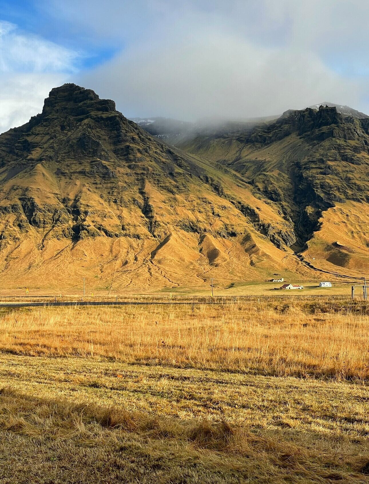 Eine gebirgige Landschaft mit einem Tal und einigen Gebäuden in der Ferne.