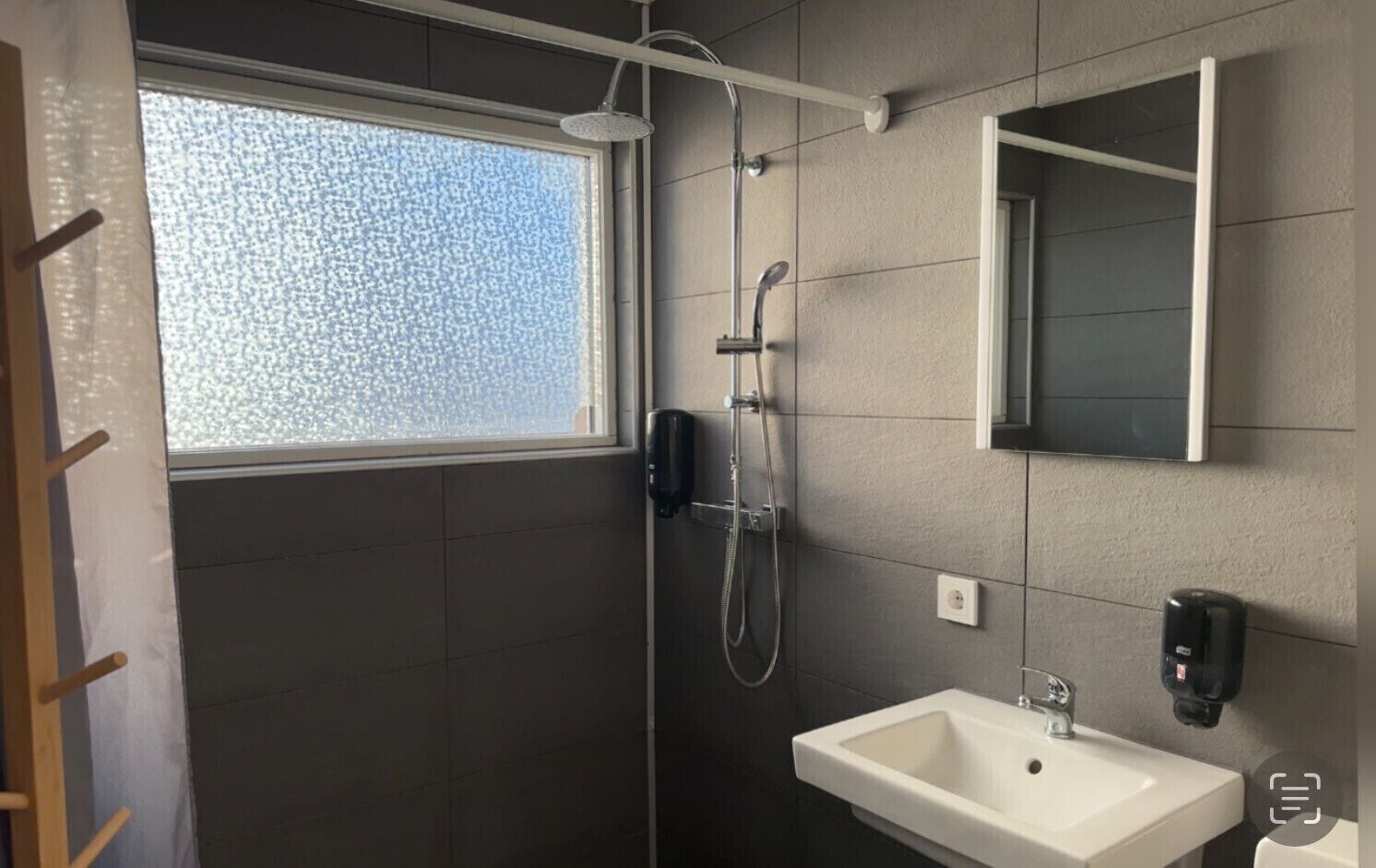 Ein modernes Badezimmer mit Dusche, Waschbecken und Fenster.