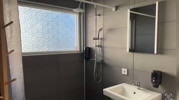 Ein modernes Badezimmer mit Dusche, Waschbecken und Fenster.