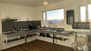A modern kitchen with a central island, a window with a view, and a dish rack. - Starlight Camping Pods (Rangárþing eystra)