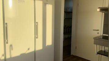 A kitchen with two white refrigerators, a wooden floor, and a small countertop with a sink.