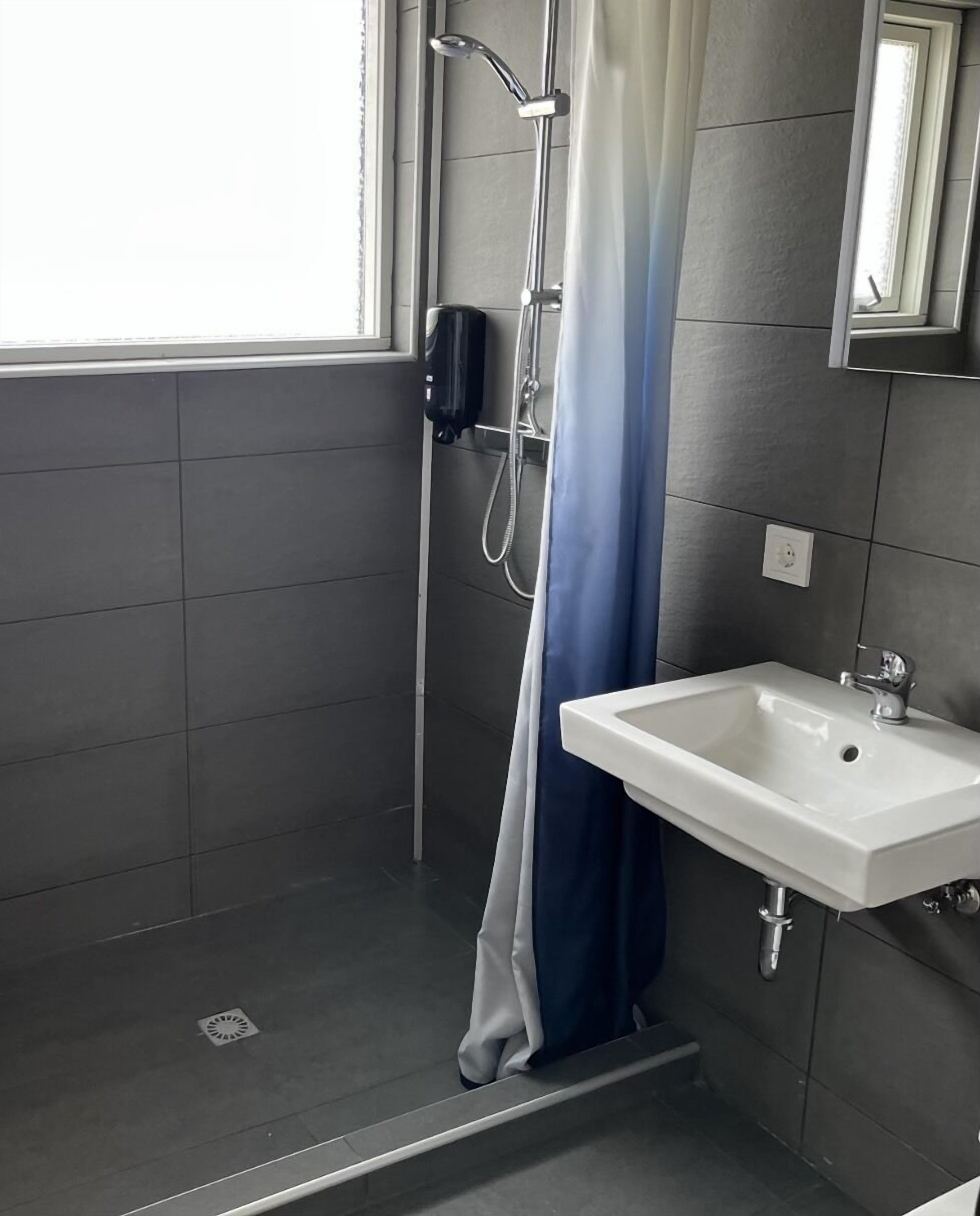 A bathroom with a shower, a sink, and a window.