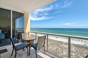 A balcony with a view of the ocean and a pier. There are two chairs and a small table. - Stella Marina - Caribbean Resort 502.Bch srvc incl!!! (Navarre)