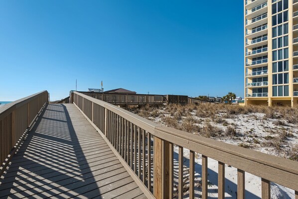 A wooden boardwalk leading to a beach with a building in the background. - Stella Marina - Caribbean Resort 502.Bch srvc incl!!! (Navarre)