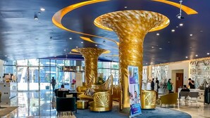 Een ruime lobby met een marmeren vloer, grote gouden zuilen en een receptiebalie.