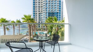 Een balkon met twee stoelen en een tafel, met uitzicht op een stadsbeeld en een wateroppervlak.