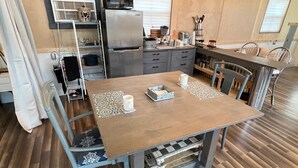 Une cuisine de taille réduite avec une table en bois, deux chaises et un réfrigérateur.