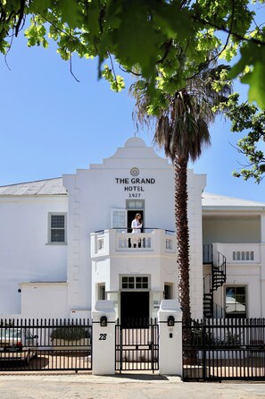 The Grand Hotel with a white facade, a balcony, and a palm tree in front. - The Grand Hotel Robertson (Robertson)