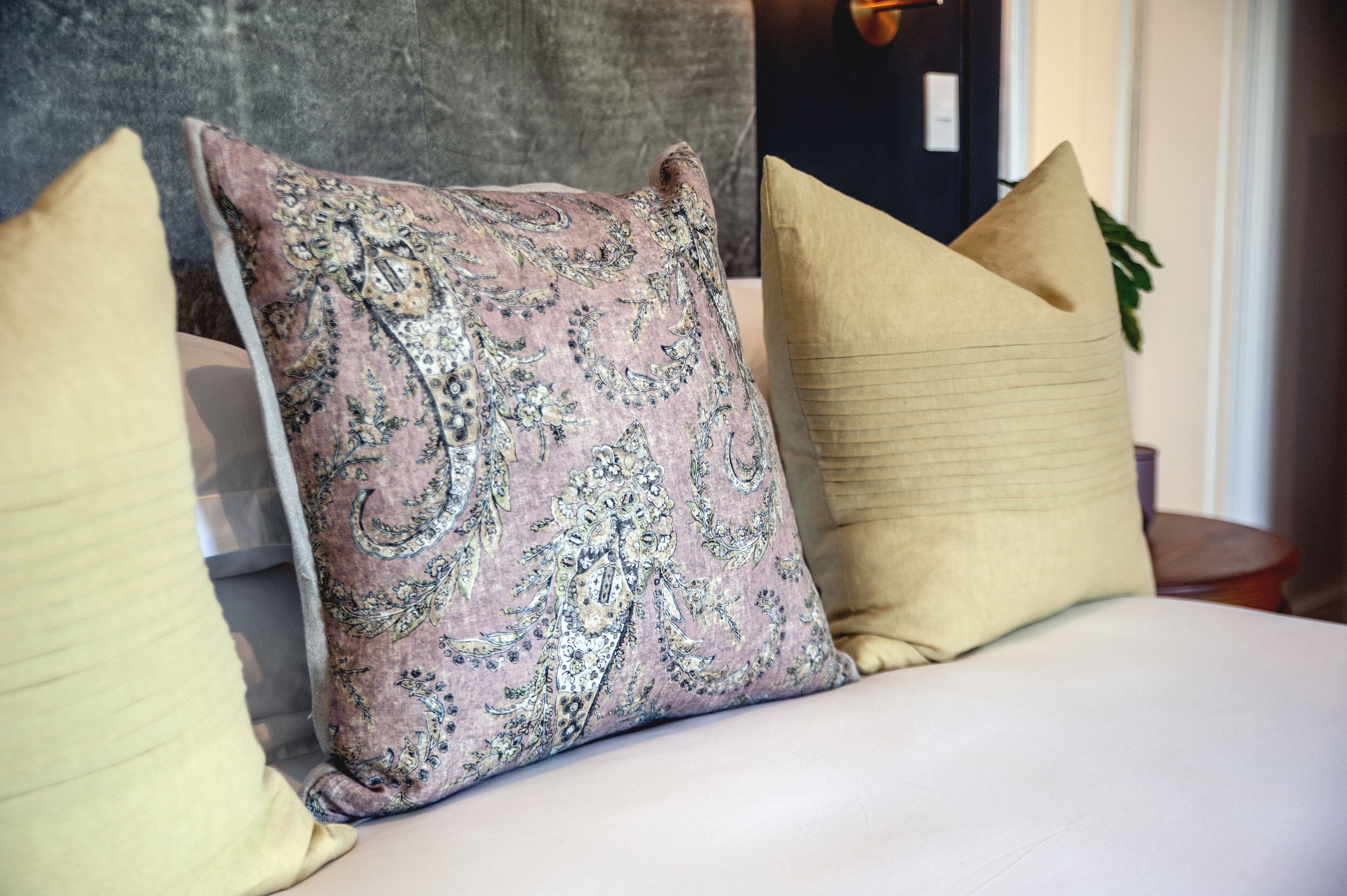 Una cama con tres almohadas, una con estampado paisley y dos lisas.